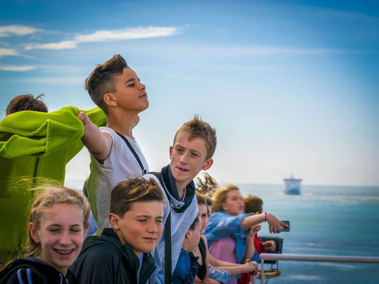 Jugendliche am Deck eines Schiffes genießen den Ausblick.