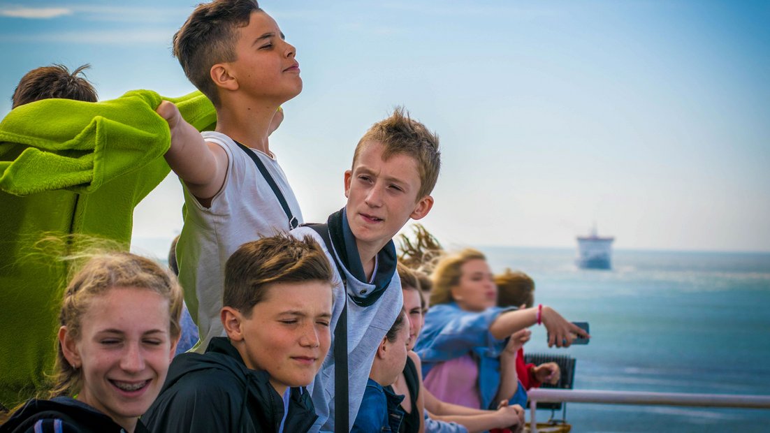 Jugendliche am Deck eines Schiffes genießen den Ausblick.