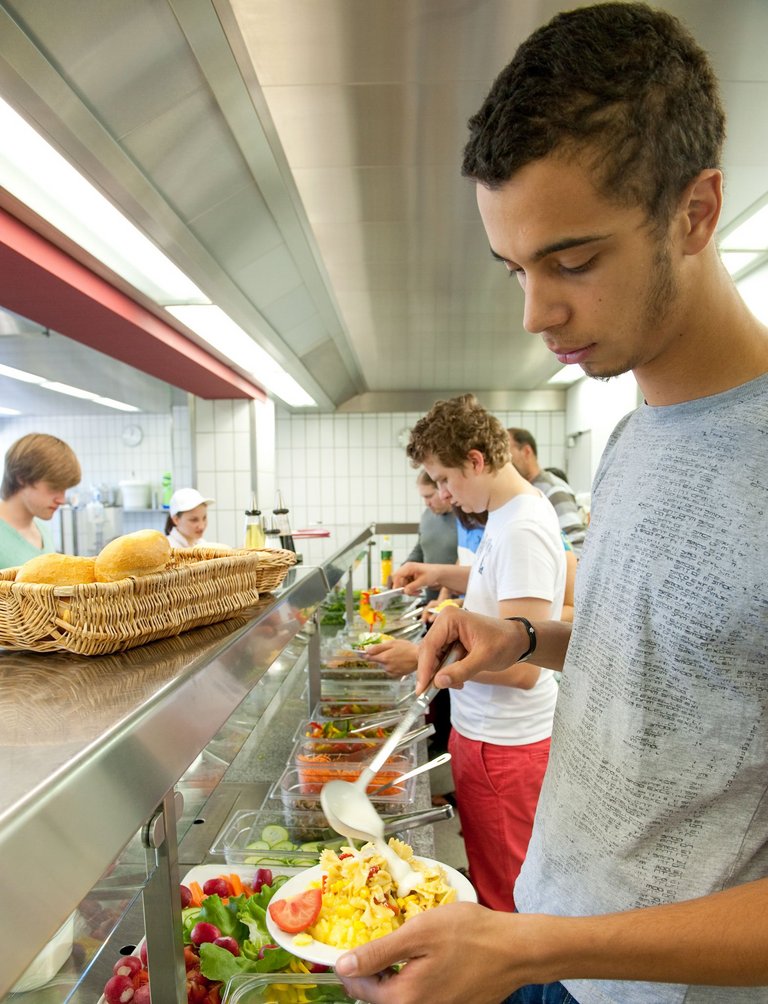 Schüler stellt sich sein Mittagsmenü an der Theke zusammen. 