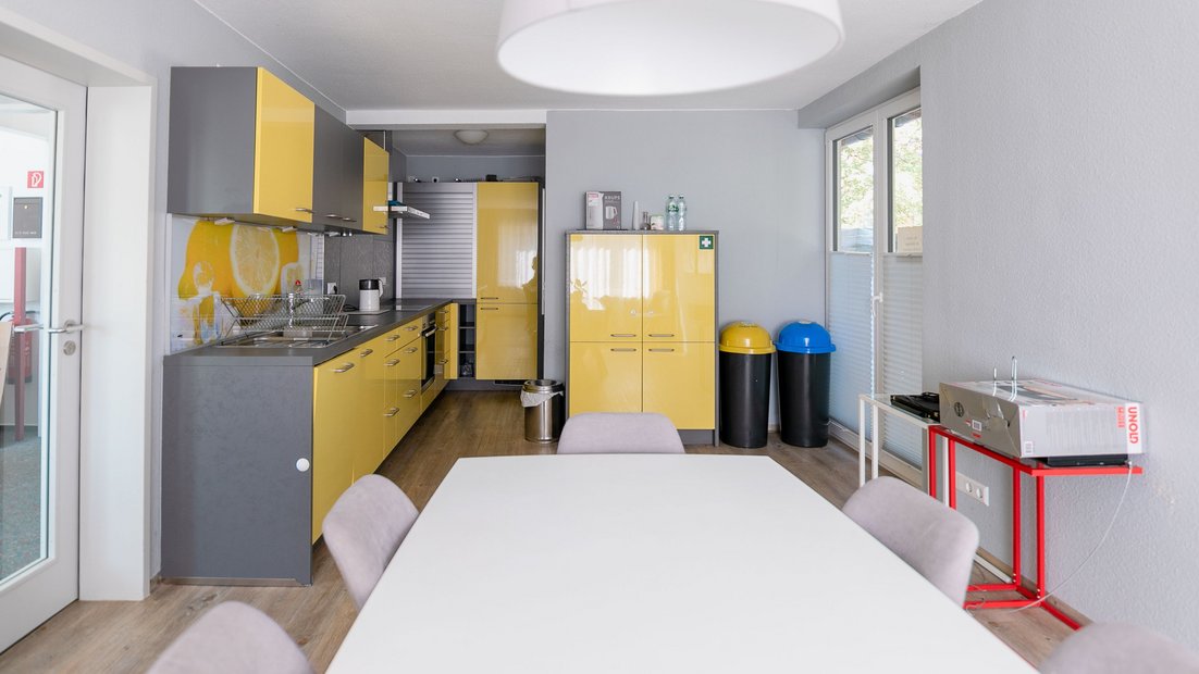 Moderne Küchenzeile in grau-gelb mit Esstischgruppe im Vordergrund