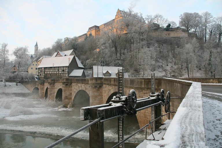 Winterlicher Blick in Richtung Steinbrücke mit Rundbögen und Wehr auf den Schloss-Berg Kirchberg