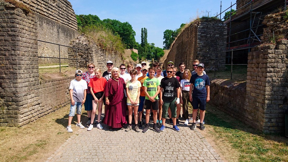 Eine Klasse steht zwischen historischen Mauern während einer Klassenfahrt nach Trier.