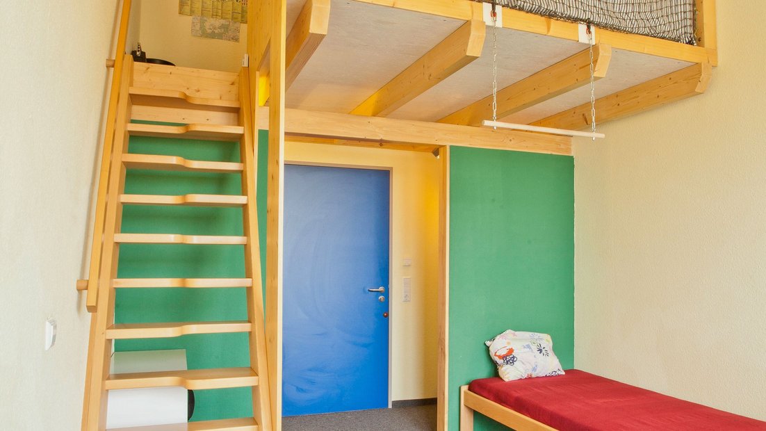 Zimmer im Wiesenhaus mit Bett und Holztreppe