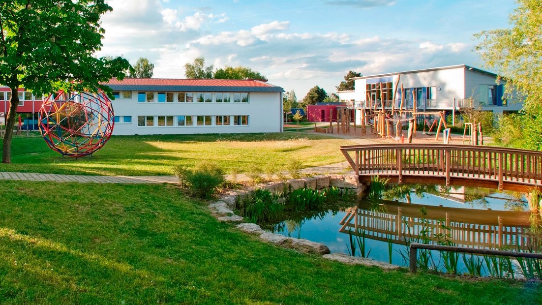 Schulgelände mit Teich und Holzbrücke