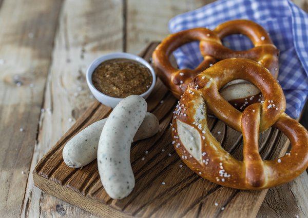 Wiesn-Essen. Bayerisches essen. Weißwürste, Brezel und süßer Senf auf Holztisch